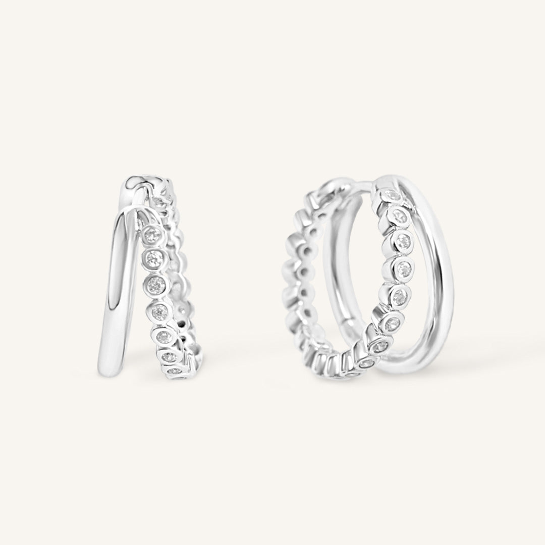 Silver hoop earrings with small stones on a white background