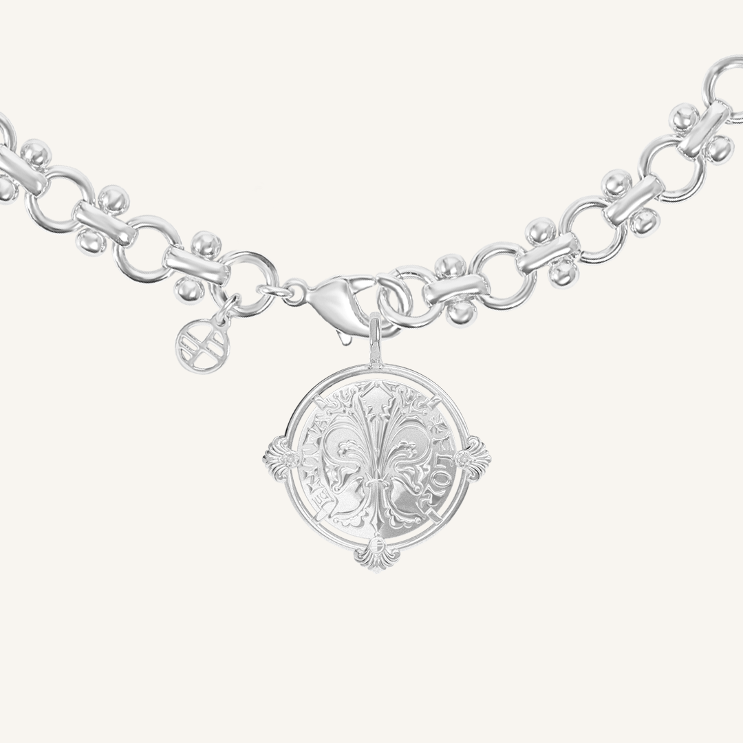 silver chain necklace inspired by Eiffel tower architecture with silver pendant featuring intricate patterns inspired by Palace of Versailles on a plain background