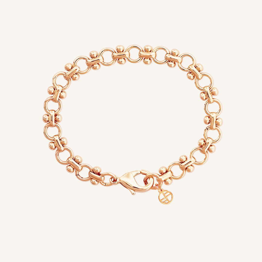 A gold-colored bracelet featuring a chain design and a decorative element shaped like the Eiffel Tower.