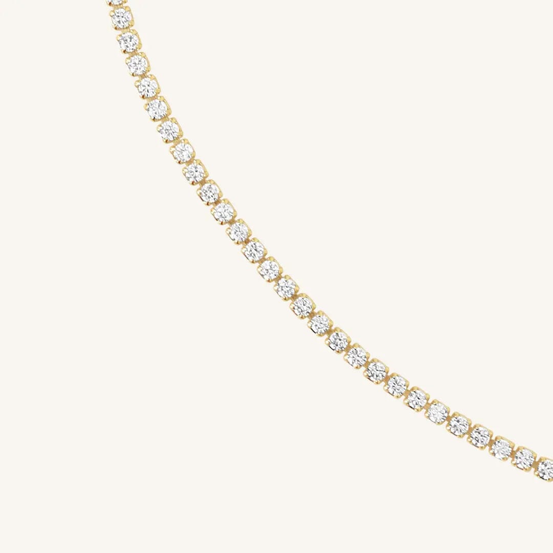 Close up of tennis chain necklace with gold metal tone.