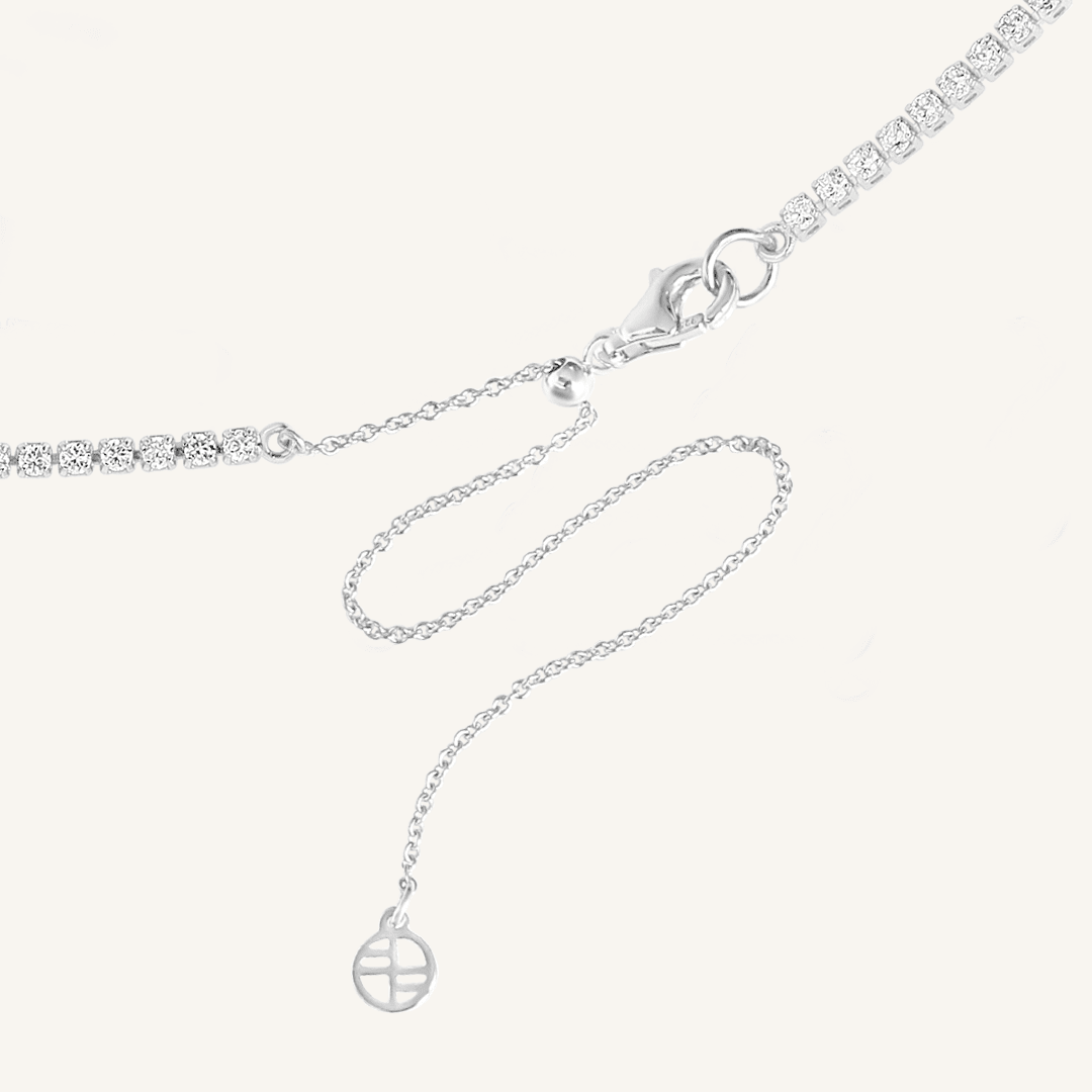 Close up of clasp on tennis chain necklace with silver metal tone.