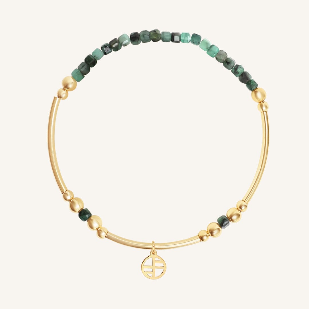 Gold bracelet with green beads and a gold charm on a white background