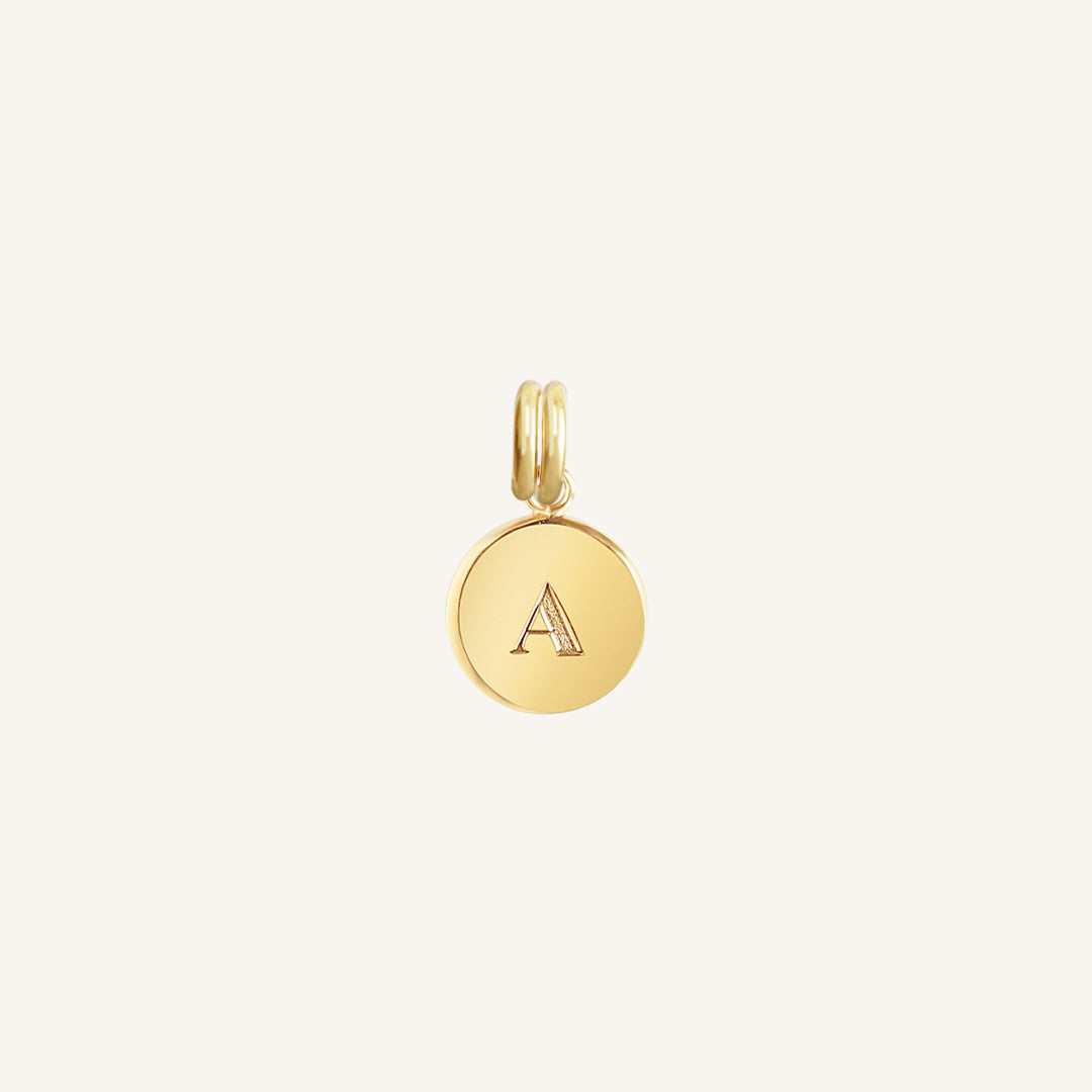 A gold round charm with the letter 'A' on it, presented against a white background.