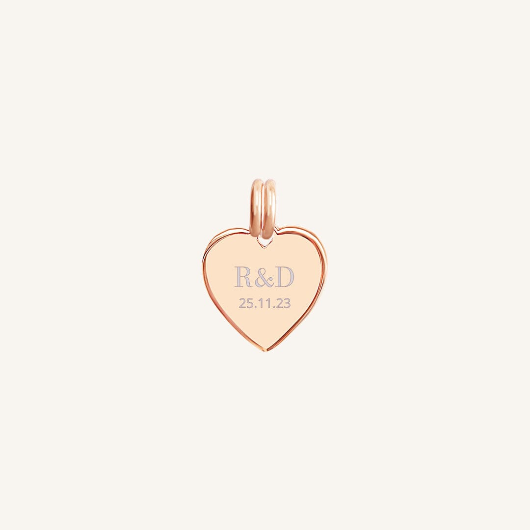 A rose heart-shaped charm with engraved initials and a date