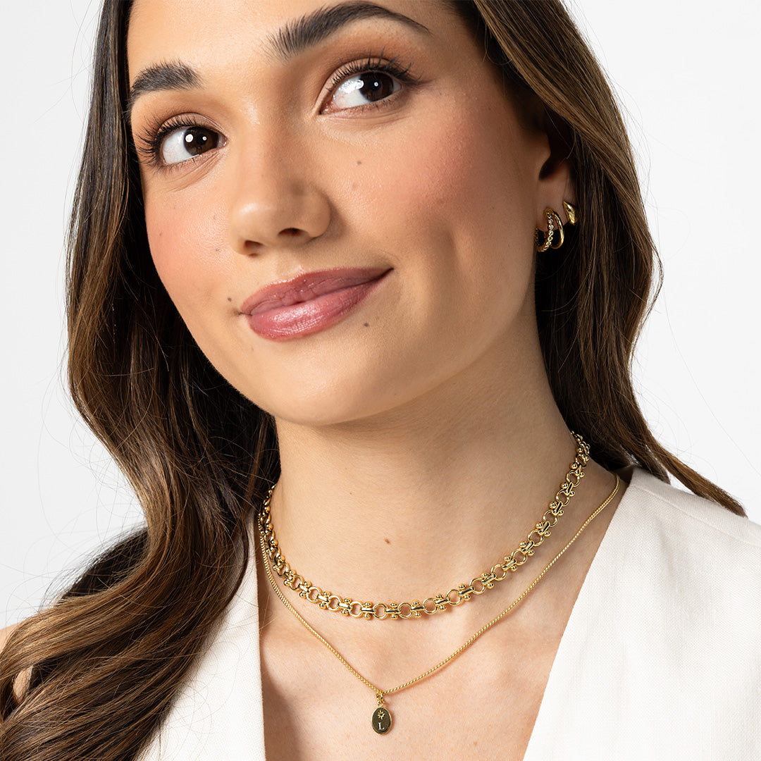 Woman wearing gold necklaces and earrings on a white background