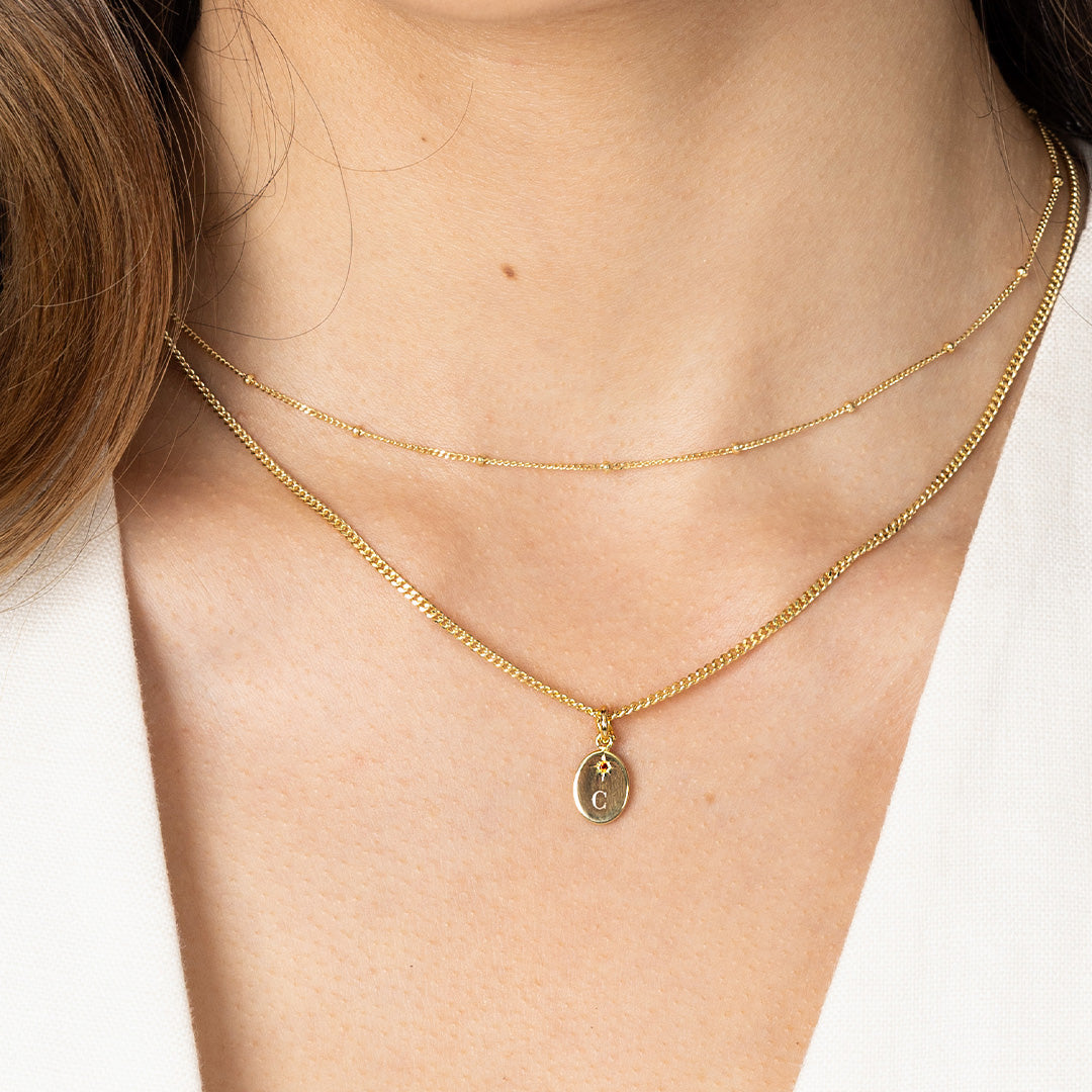 Gold necklace with a pendant on a person against a white background