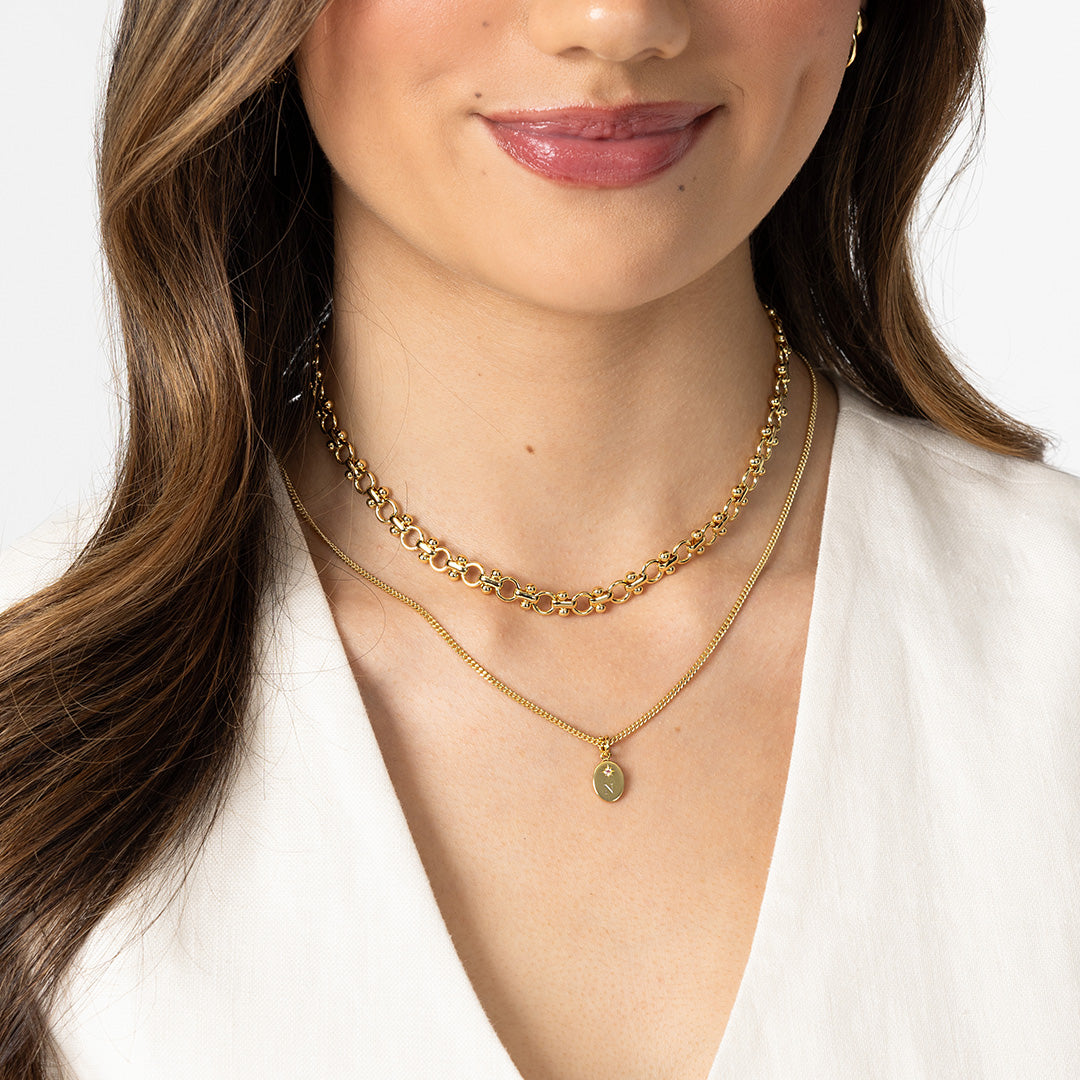 Close-up of a woman wearing two gold necklaces with a white background