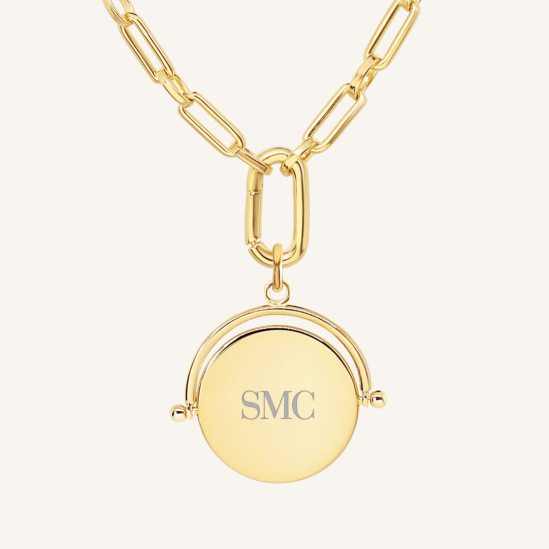 A gold-coloured, engraved pendant with, featuring a spinning mechanism, on chain