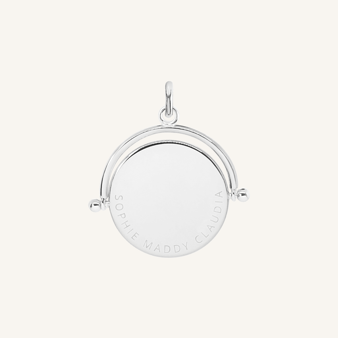 A silver-coloured, engraved pendant with, featuring a spinning mechanism.