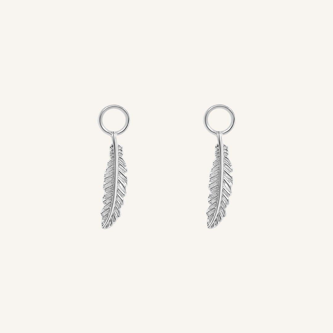 A set of two silver hoop charms with a feather design, on white background