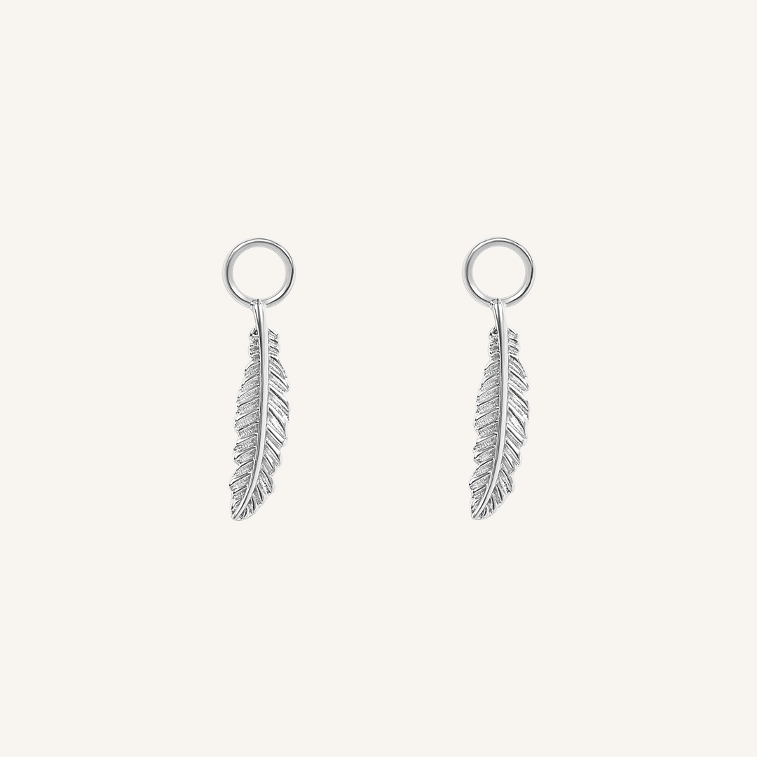 A set of two silver hoop charms with a feather design, on white background