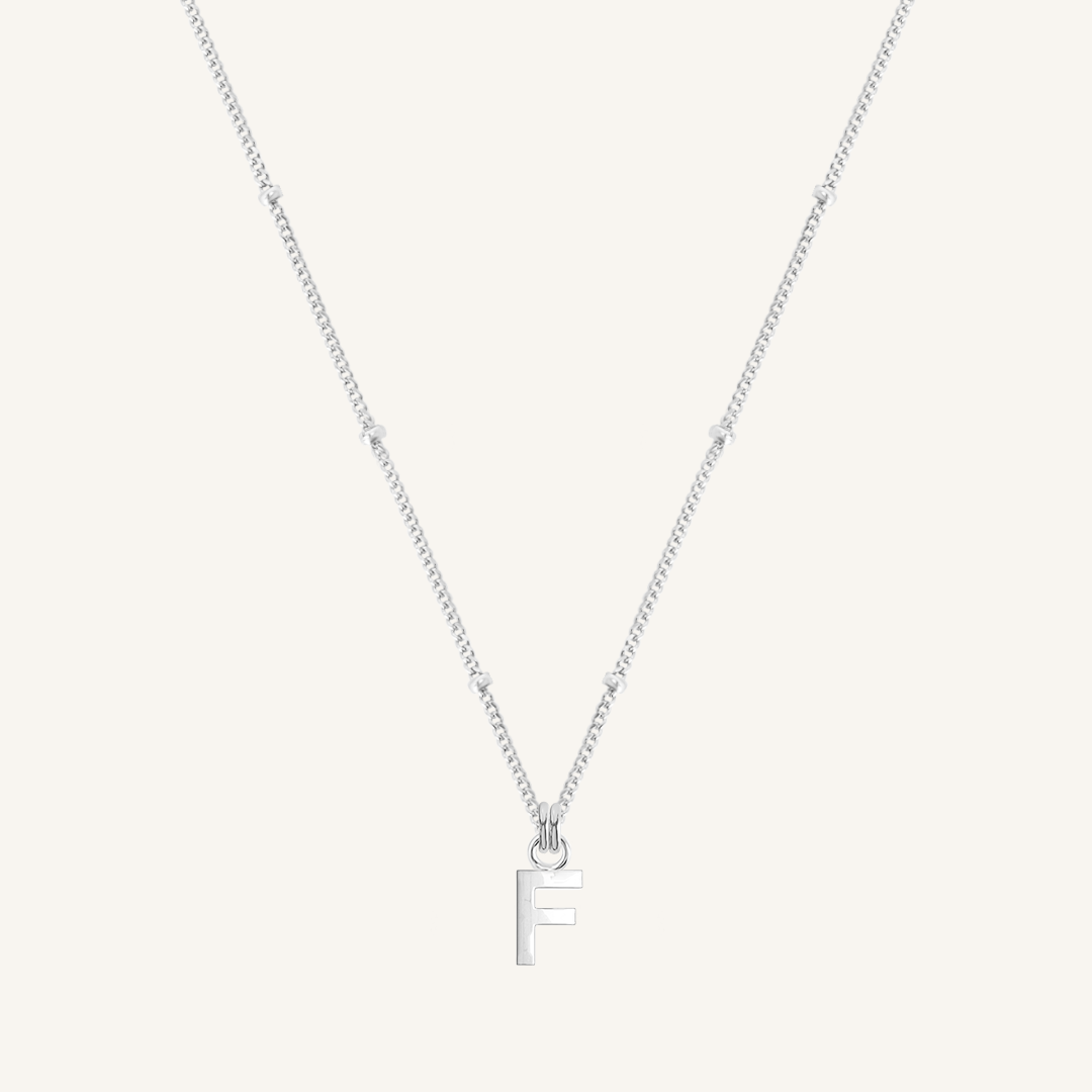 Silver necklace with a 'F' pendant on a light gray background