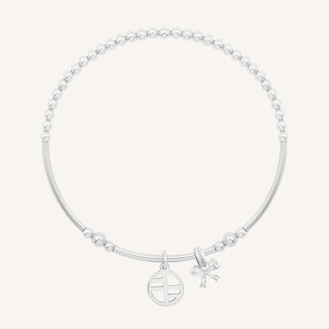 A silver-tone metal bracelet with a beaded design, featuring a charm in the shape of a bow