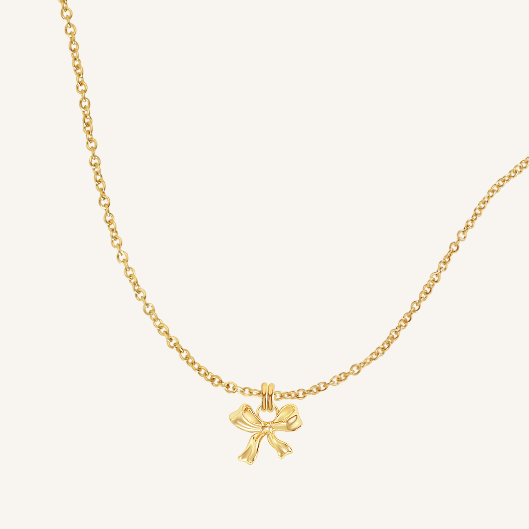 A gold-tone charm necklace with a bow pendant.