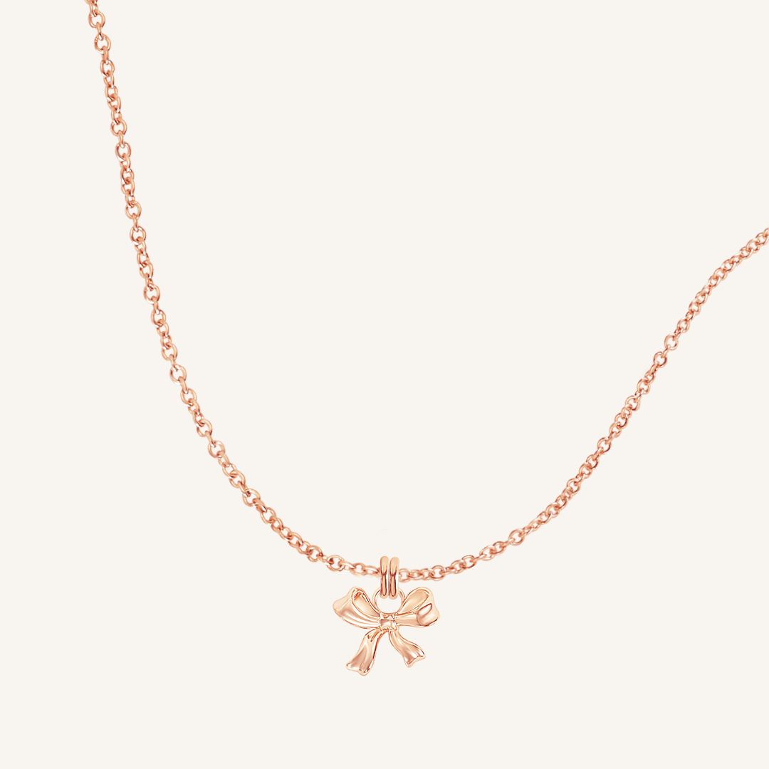 A rose-colored necklace featuring a bow-shaped charm attached to a hoop.