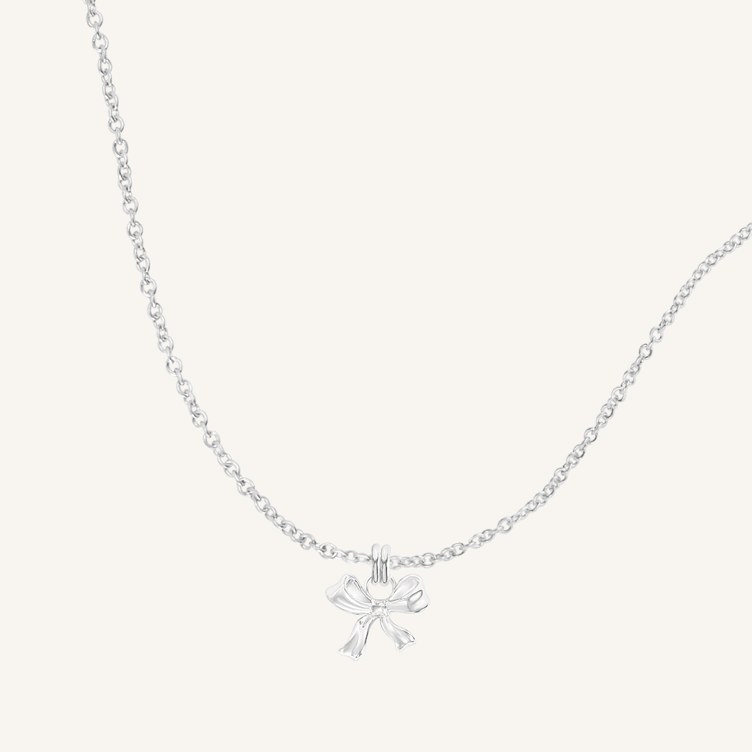 A silver-colored necklace featuring a bow-shaped charm attached to a hoop.