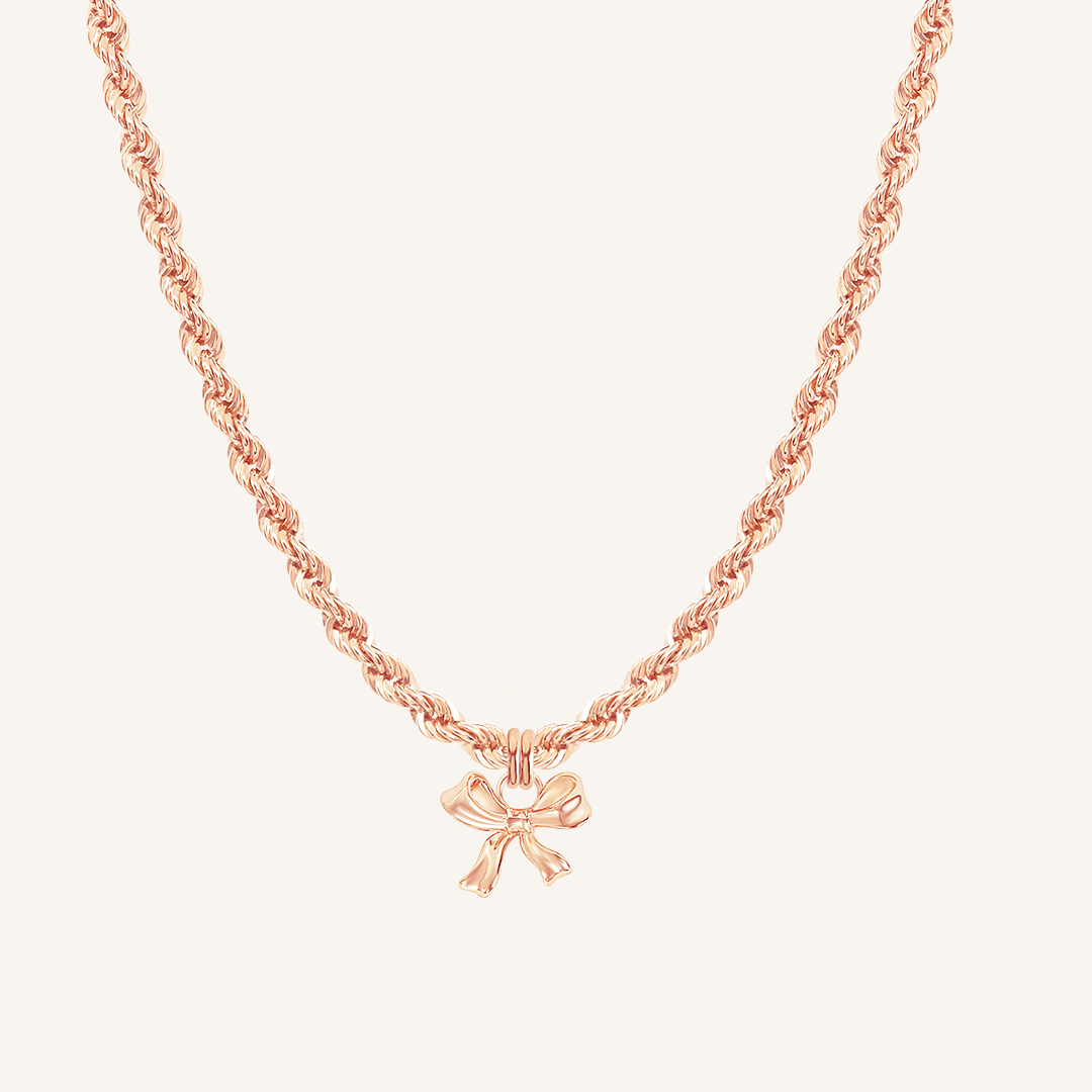 A rose-tone charm necklace with a bow pendant.
