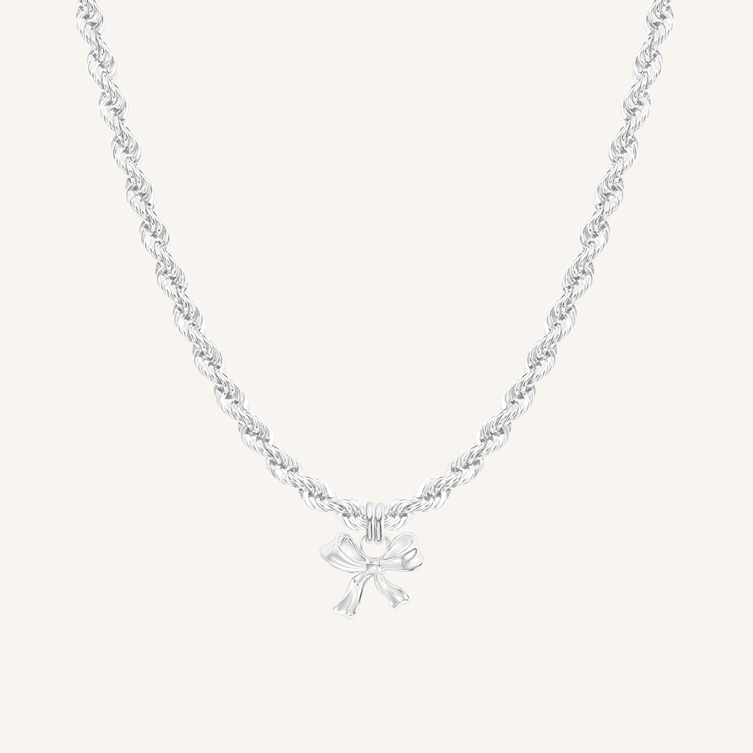 A silver-colored necklace featuring a bow-shaped charm attached to a hoop.