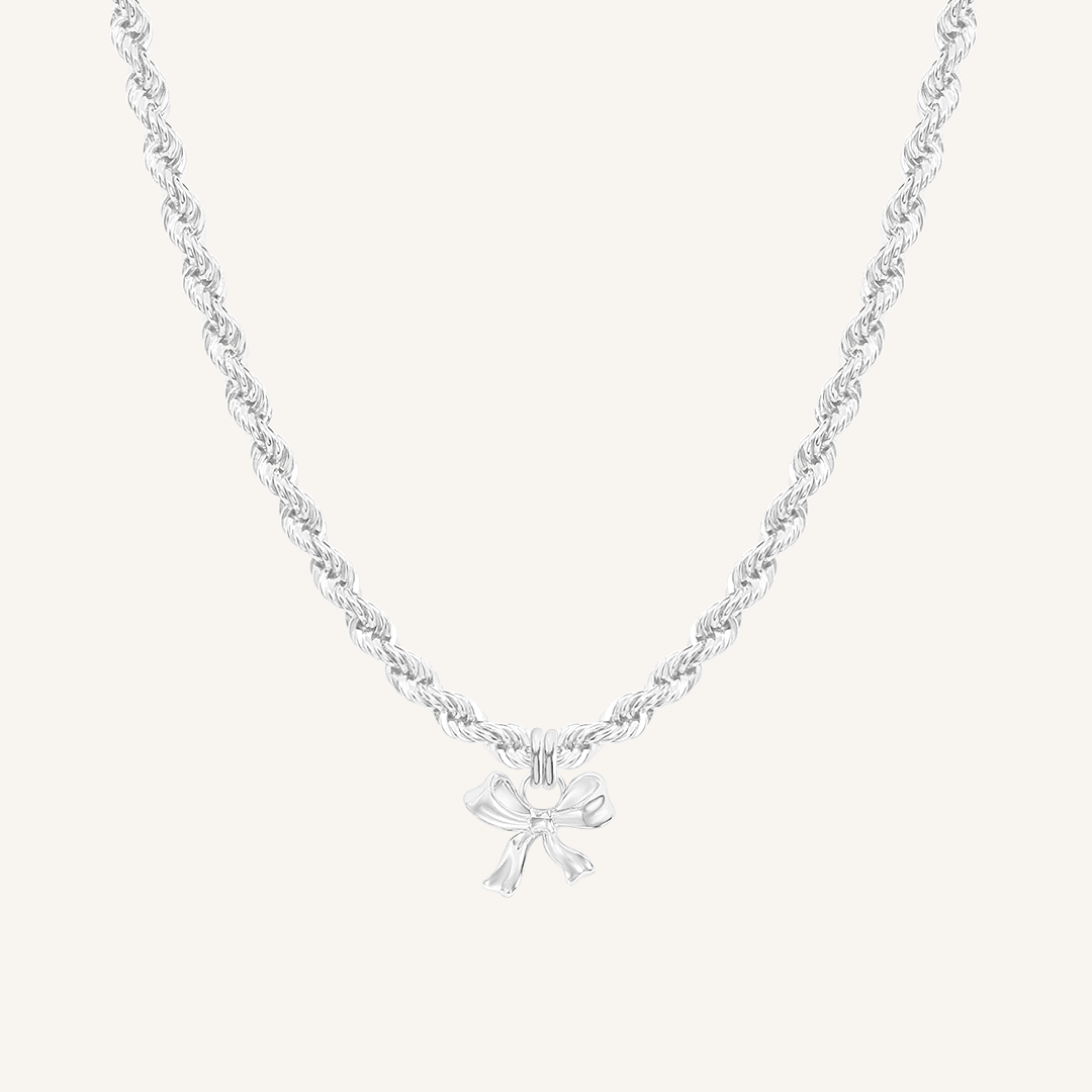 A silver-colored necklace featuring a bow-shaped charm attached to a hoop.