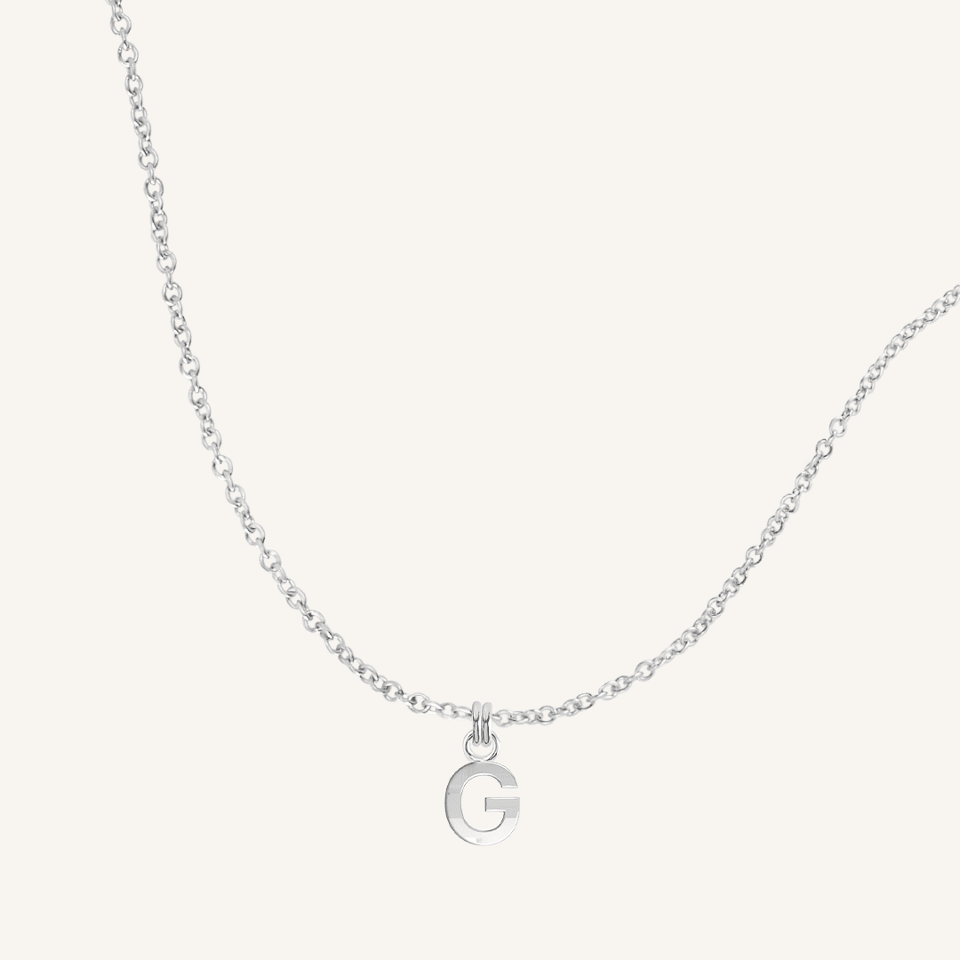 Silver necklace with a G letter pendant on a white background