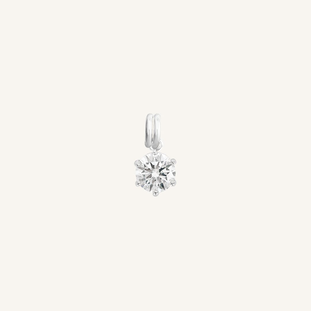 A round silver cubic zirconia charm on white background
