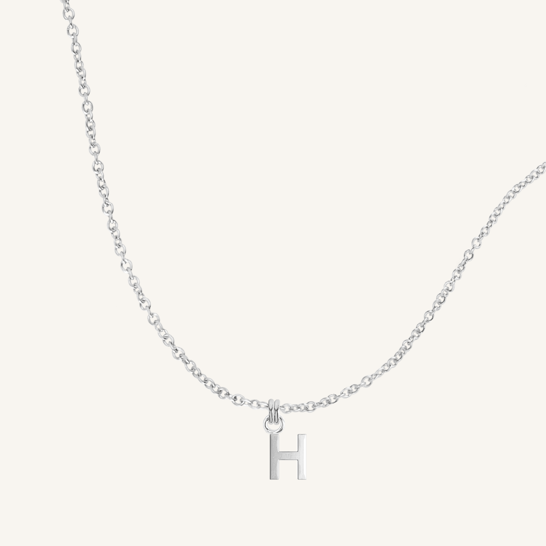 Silver necklace with a 'H' pendant on a light gray background