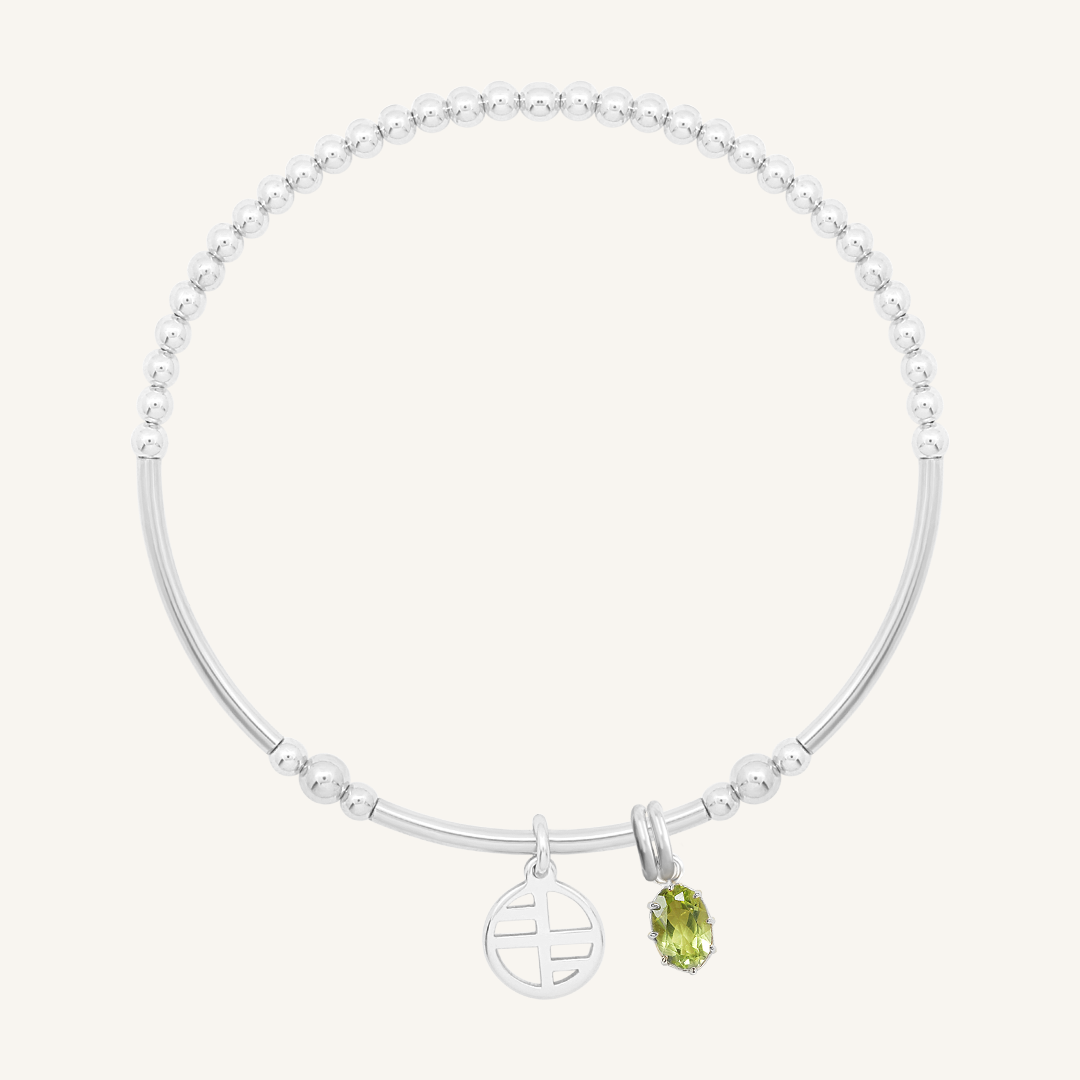 A silver-tone heritage charm bracelet with a beaded chain and a green oval charm.