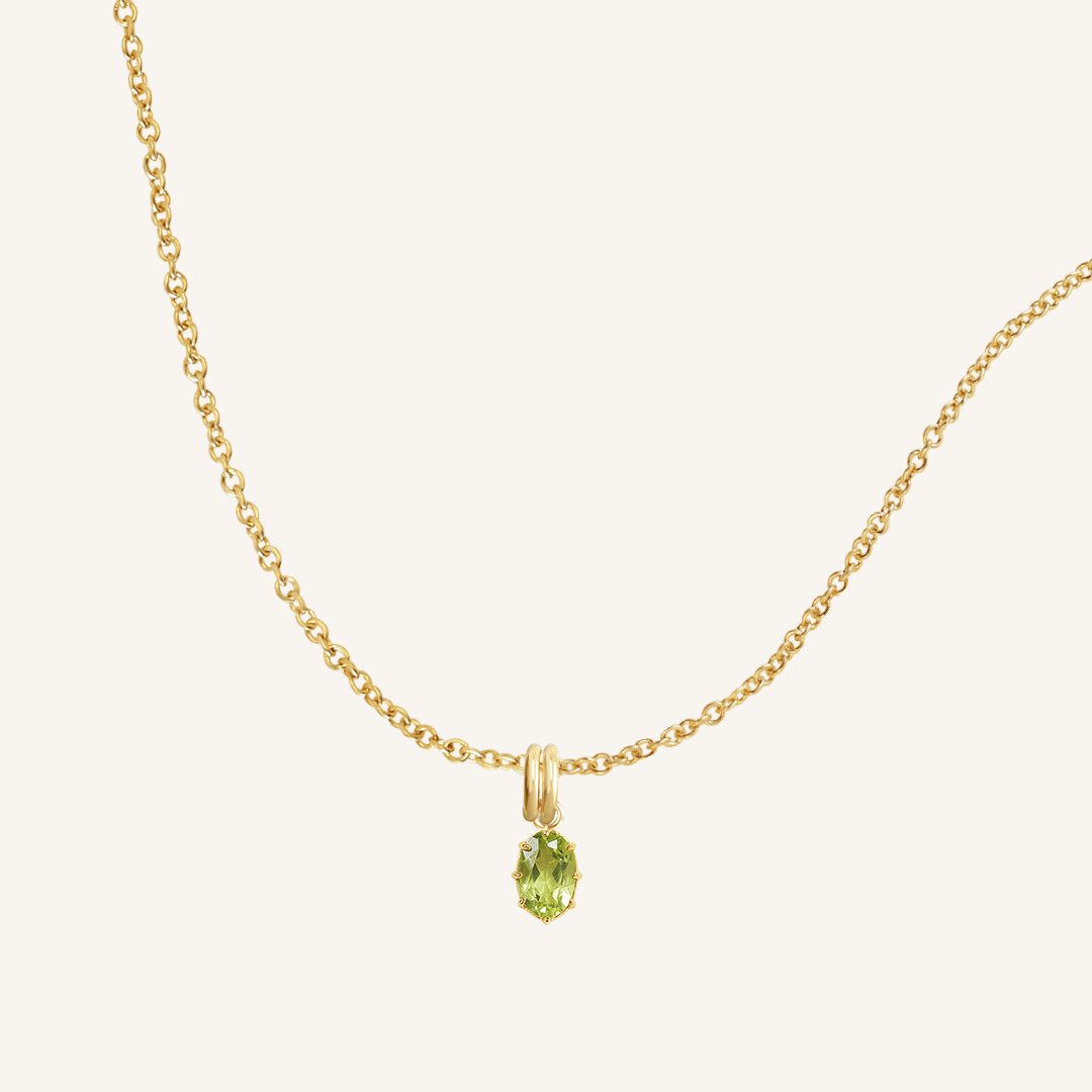 A green, oval-shaped charm pendant necklace with a gold metal chain.