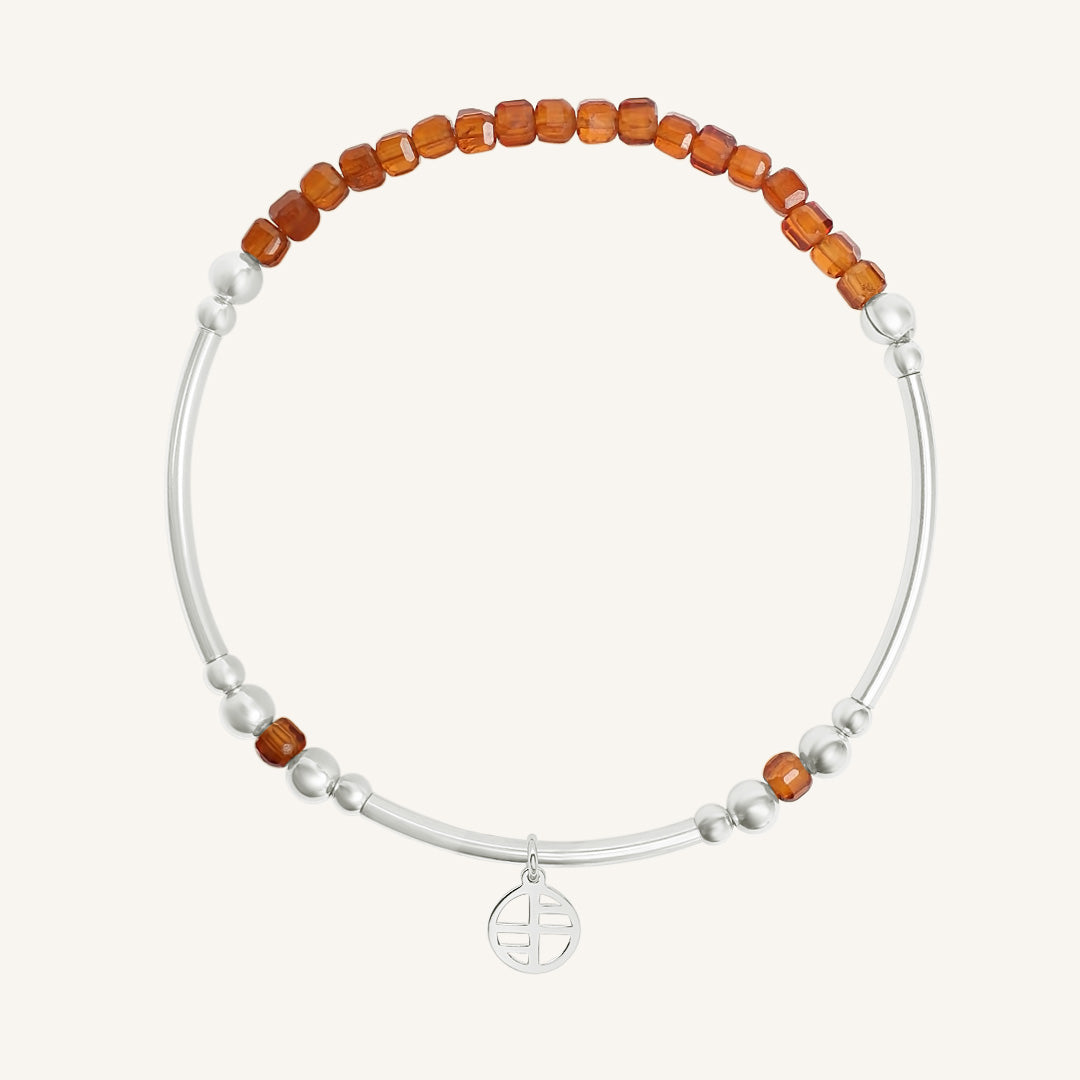 Bracelet with orange beads and a silver charm on a white background