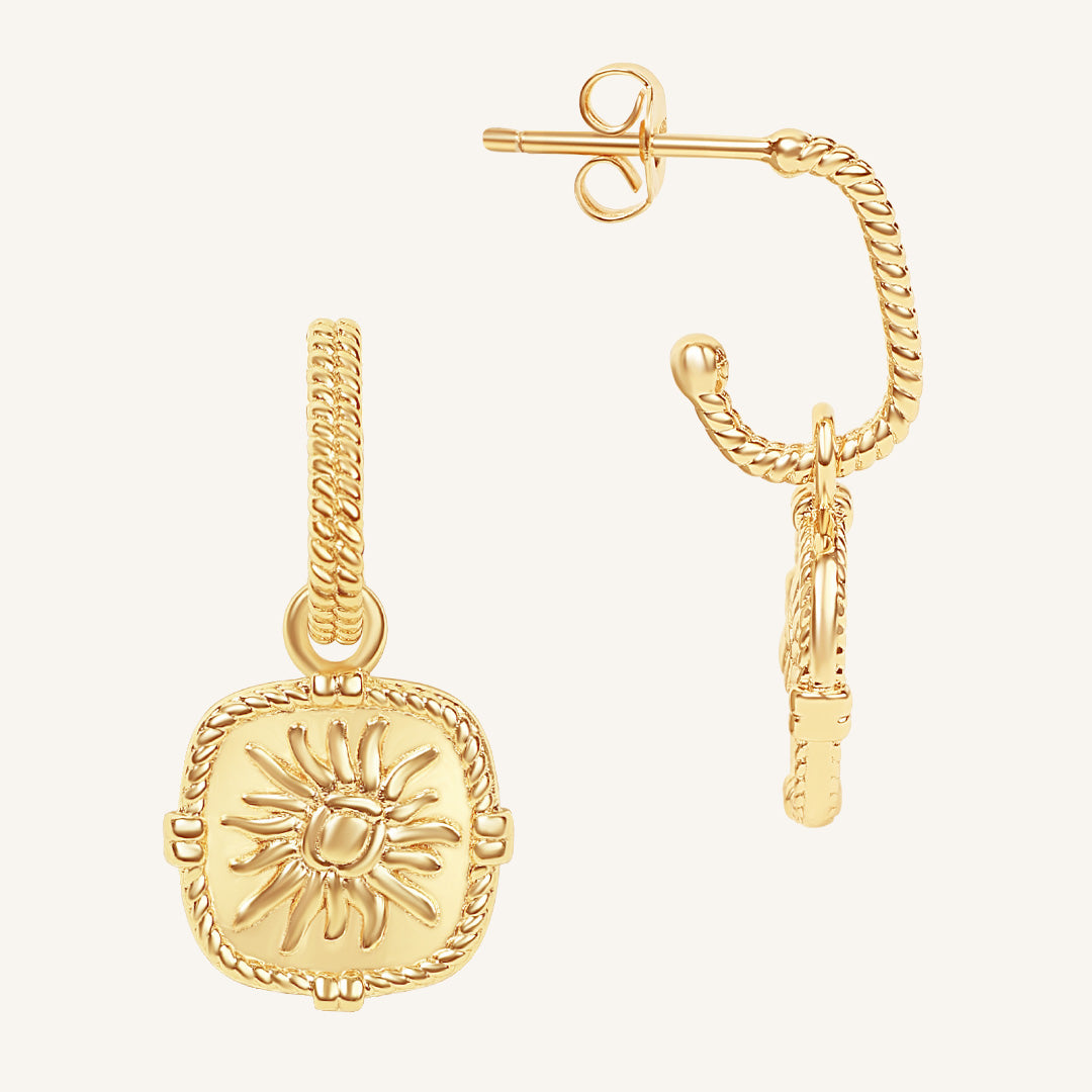 Gold sun-shaped pendant earring on a white background