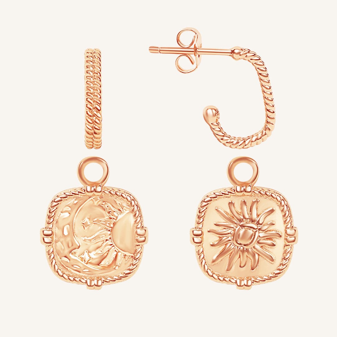 Rose gold hoop earrings with intricate designs on a light beige background