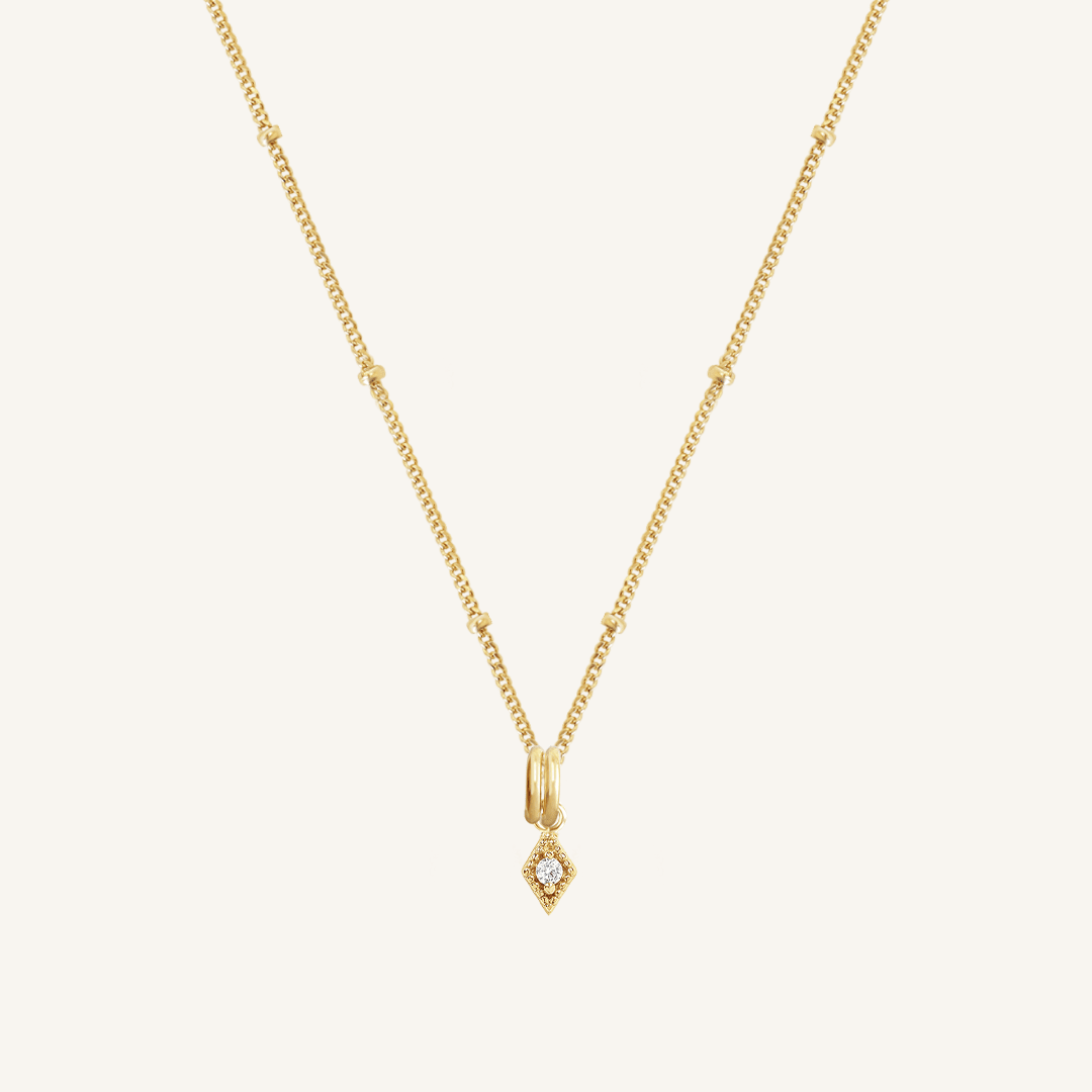 A delicate necklace featuring a small diamond charm pendant suspended from a gold-tone chain.