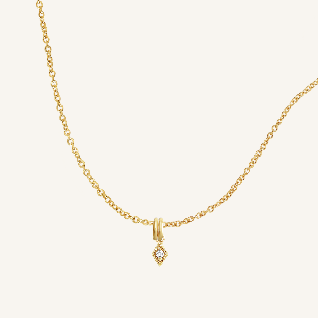 A delicate necklace featuring a small diamond charm pendant suspended from a gold-tone chain.