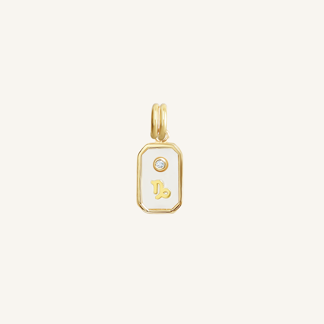 A gold rectangular shaped charm with the Capricorn zodiac symbol on it, designed with an iridescent finish.