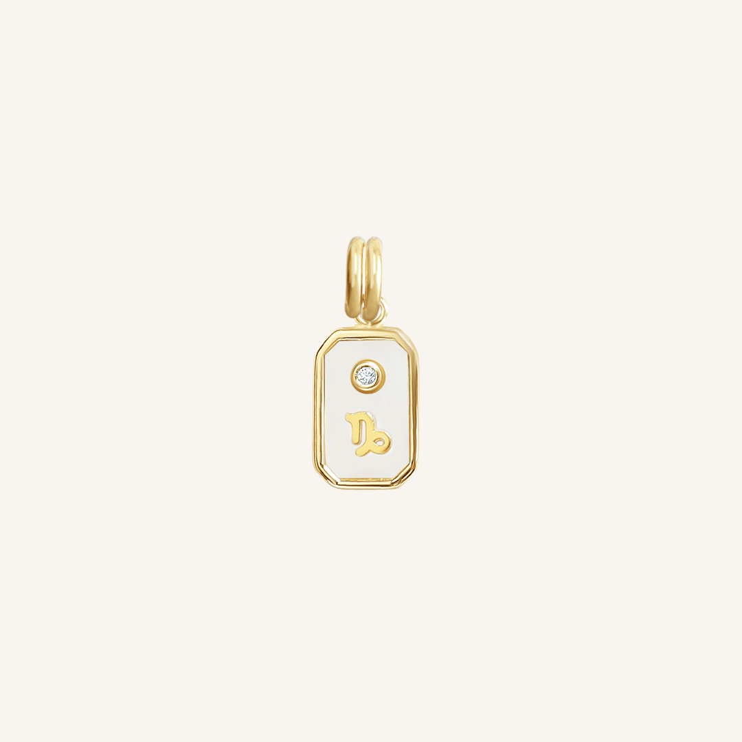 A gold rectangular shaped charm with the Capricorn zodiac symbol on it, designed with an iridescent finish.