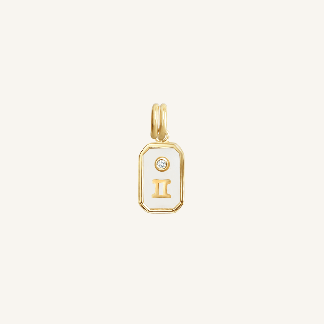 A gold rectangular shaped charm with the Gemini zodiac symbol on it, designed with an iridescent finish.