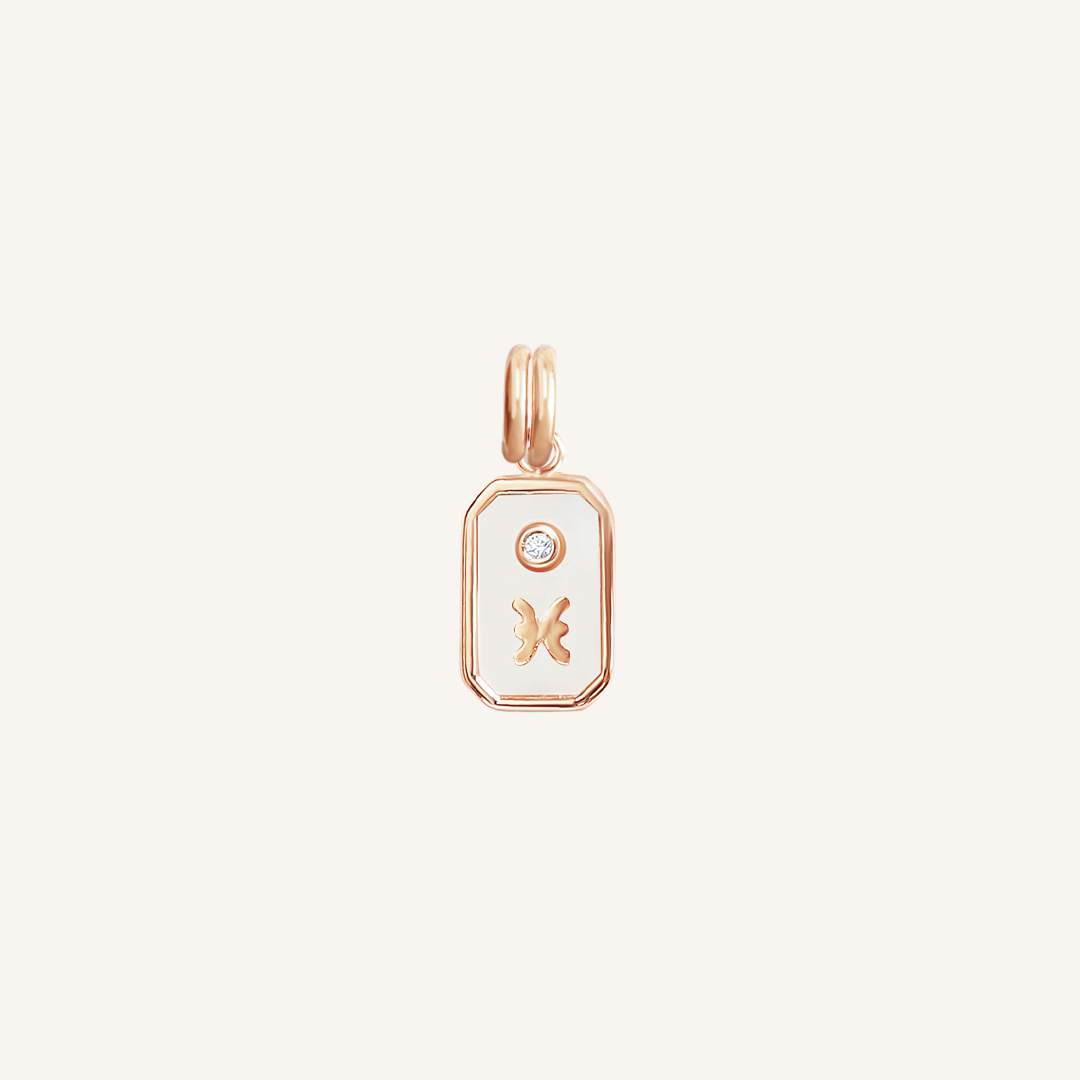 A rose gold rectangular shaped charm with the Pisces zodiac symbol on it, designed with an iridescent finish.