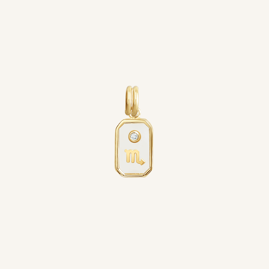 A gold iridescent zodiac charm featuring the sign for Scorpio.