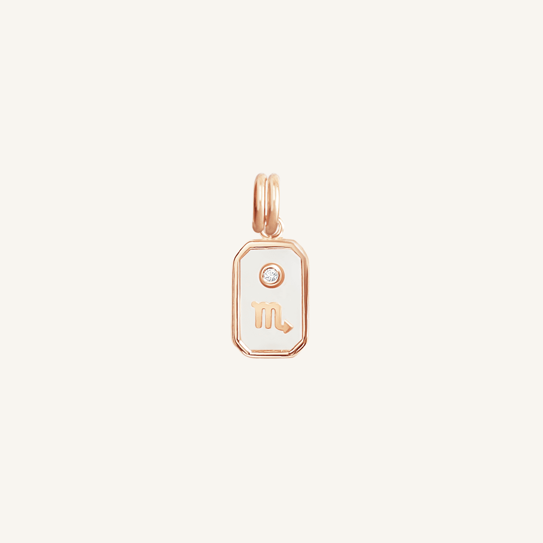 A rose gold iridescent zodiac charm featuring the sign for Scorpio.