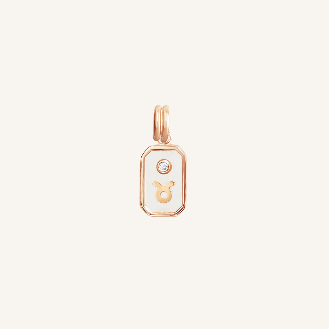 A rose gold iridescent zodiac charm representing the Taurus sign, with a loop for attachment