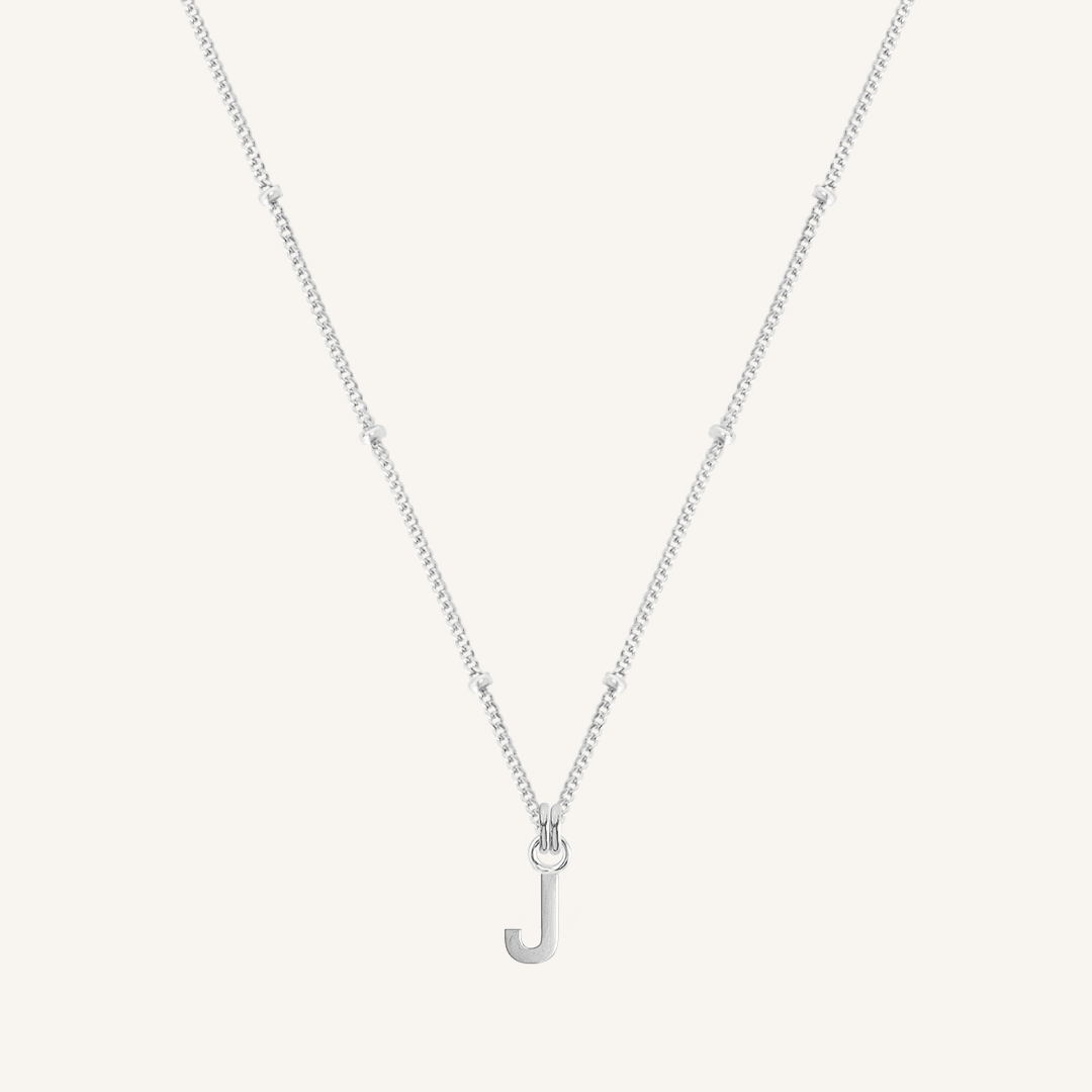 Silver necklace with a 'J' pendant on a light gray background