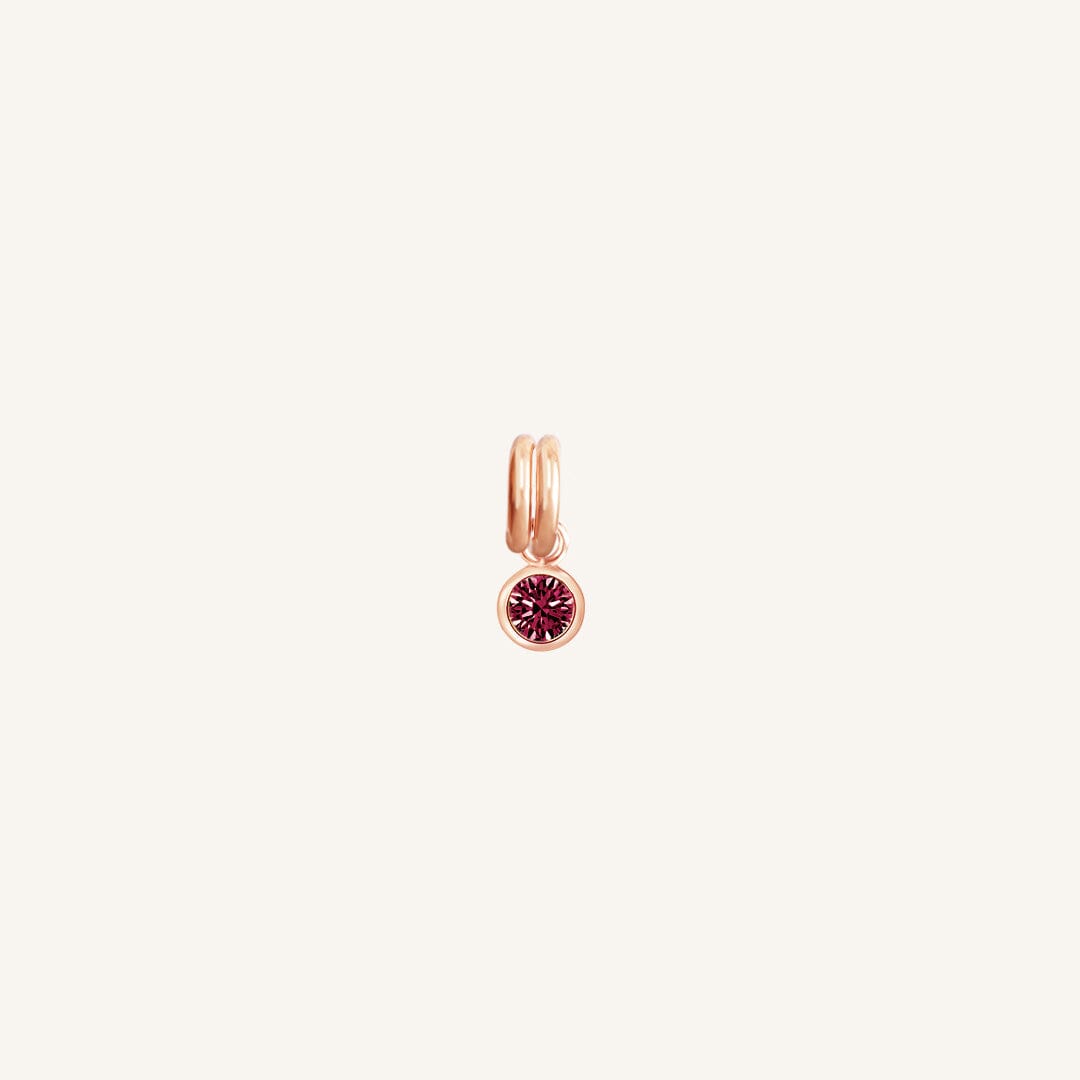 Round rose gold charm with bezel-set ruby cubic zirconia representing the July birthstone.