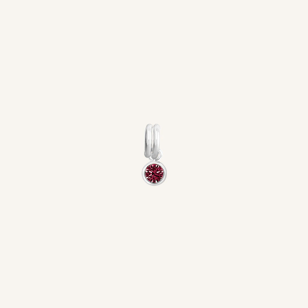 Round silver charm with bezel-set ruby cubic zirconia representing the July birthstone.