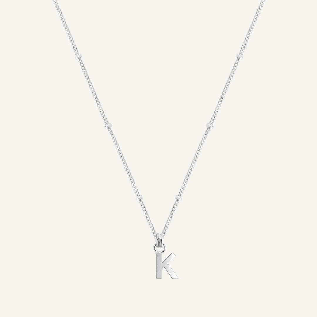 Silver necklace with a 'K' pendant on a light gray background