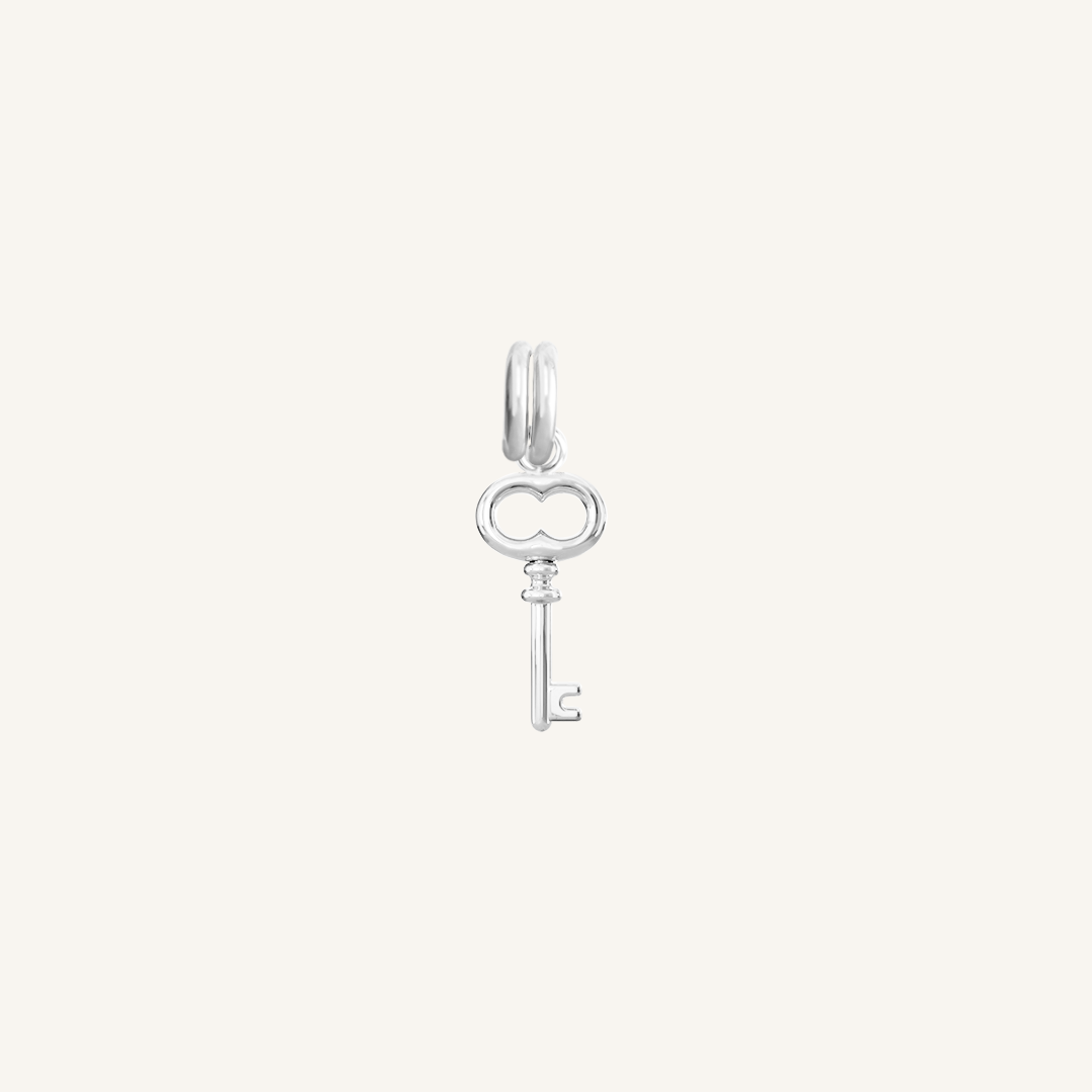 A silver key charm on a plain background
