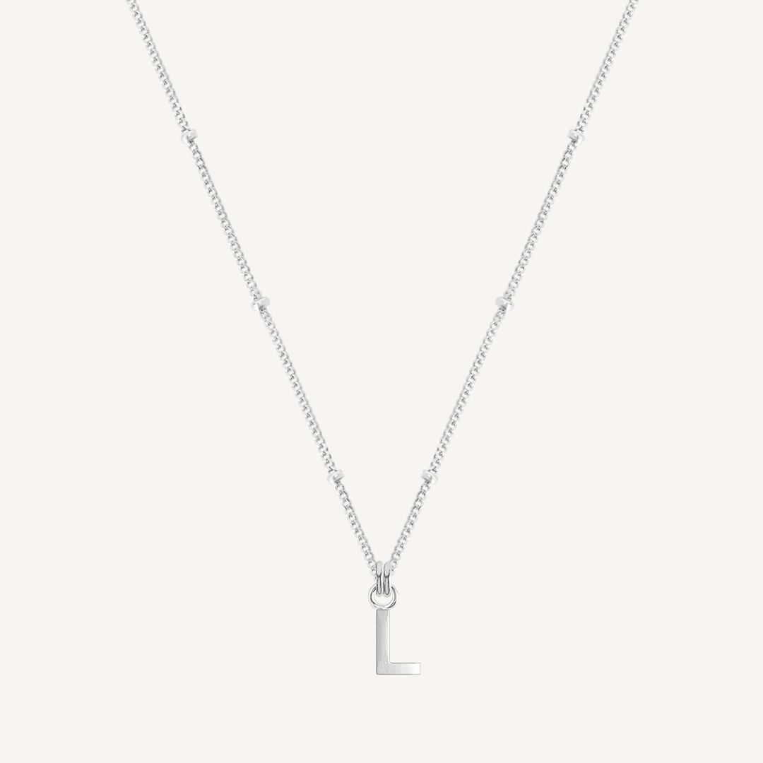 Silver necklace with a 'L' pendant on a light gray background