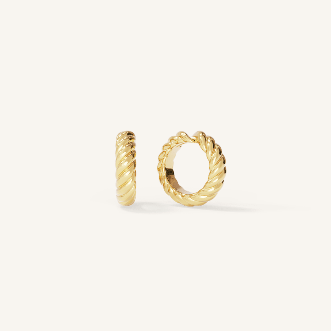 gold delicate huggies with a twist design on white background