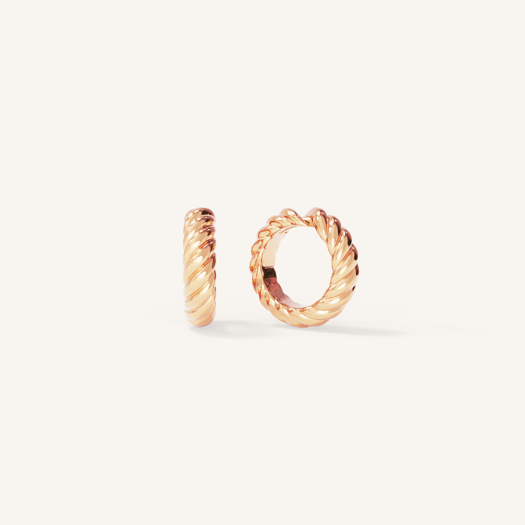 rose gold delicate huggies with a twist design on white background