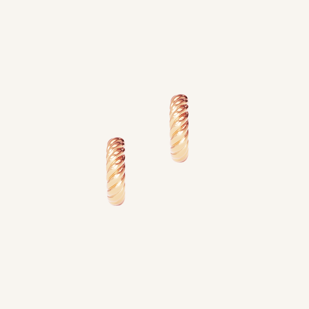 rose gold delicate huggies with a twist design on white background