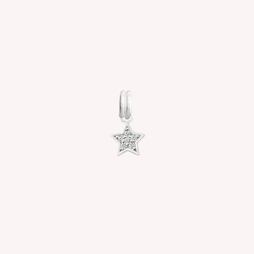 A silver coloured charm in the shape of a star with a small cubic zirconias, designed to be attached to a bracelet or chain.